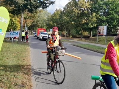Auf dem Foto sieht man verschiedene Radfahrer mit Helmen, Warnwesten und Abstandshaltern. Im Hintergrund befindet sich ein VCD Banner.
