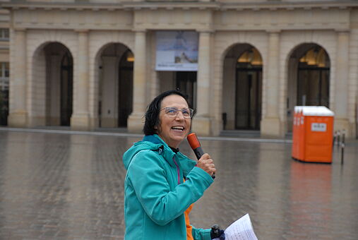 Auf dem Bild ist Birgitt Heine vom ADFC Cottbus zu sehen. Sie hält ein Mikrofon und schaut in die Kamera. 