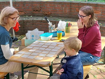 Zwei VCD Mitglieder spielen mit einem Kind ein Verkehrsmemory.